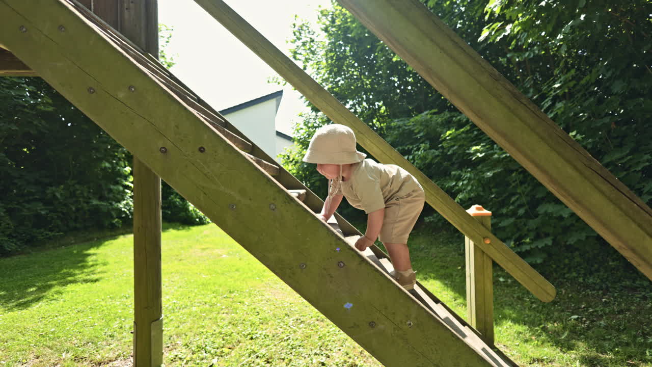 Toddler climbs the stairs to the slide. Child plays on the playground. Little boy learns to walk on the stairs. Child development. Toddler walk in the fresh air