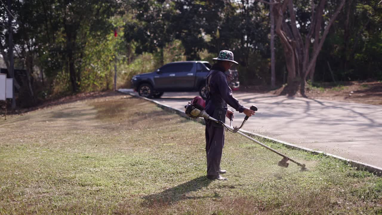 Person cutting grass with a string trimmer