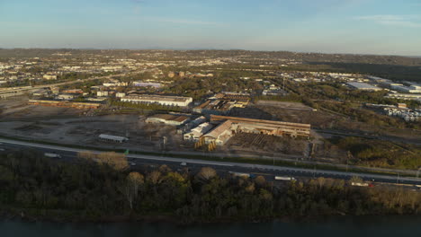 Slow-aerial-rotating-pan-across-an-abandoned-industrial-steel-yard-next-to-highway-24-in-Chattanooga,-TN-during-the-sunset