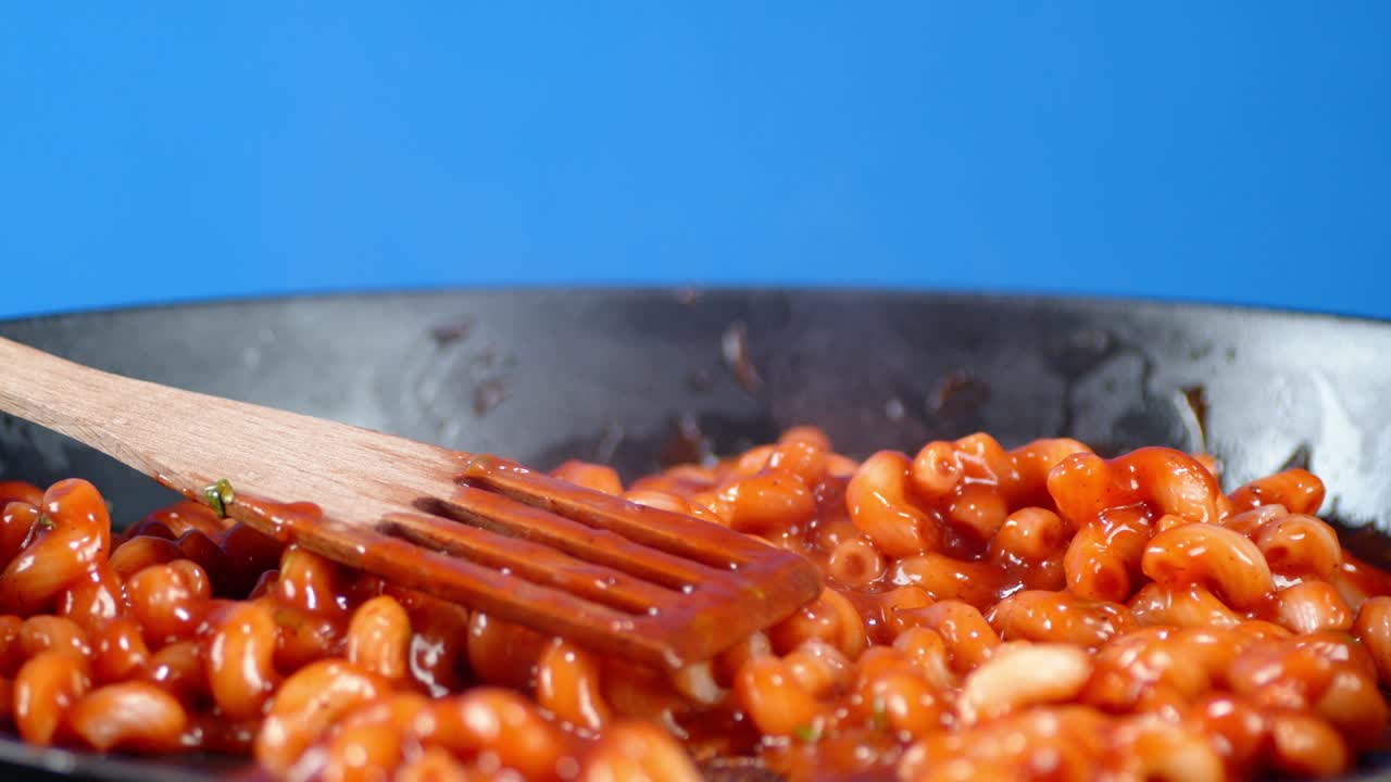 Boiled pasta cavatappi in pan with tomato sauce slowly rotates.