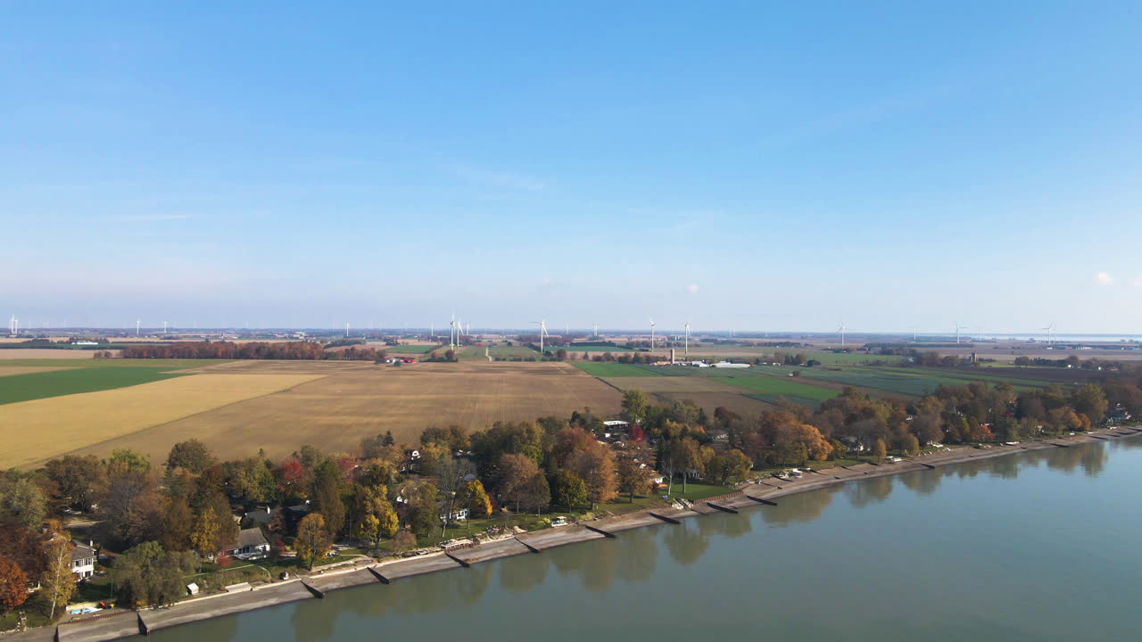 Jetty's poke out along lake shoreline edge with wind turbines behind