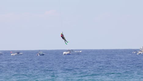 persona en parapente sobre el mar, barcos en el fondo