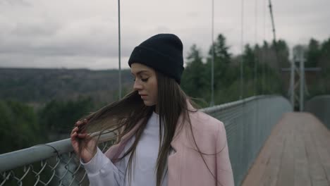 dama atractiva acariciando su cabello largo mientras camina en el puente durante el invierno en coaticook, quebec, canadá, toma en cámara lenta