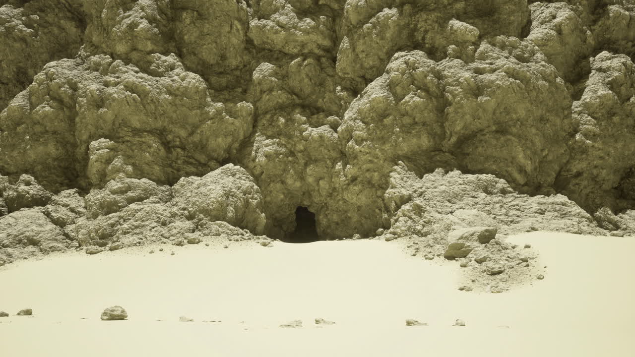Rocky cave entrance surrounded by textured sandy landscape at midday