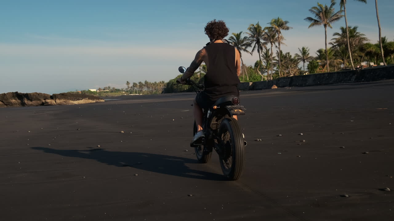 hombre en una motocicleta en una playa de arena negra