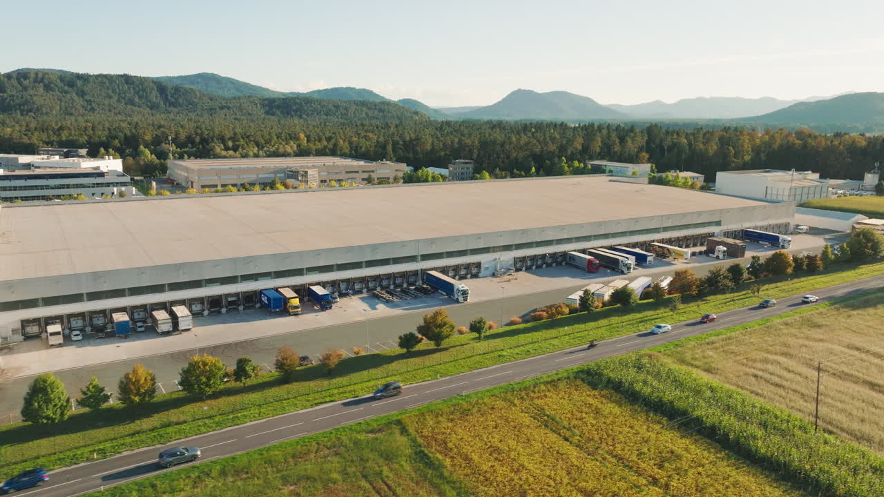 Large logistics center shows trucks loading and unloading cargo in the distribution area with