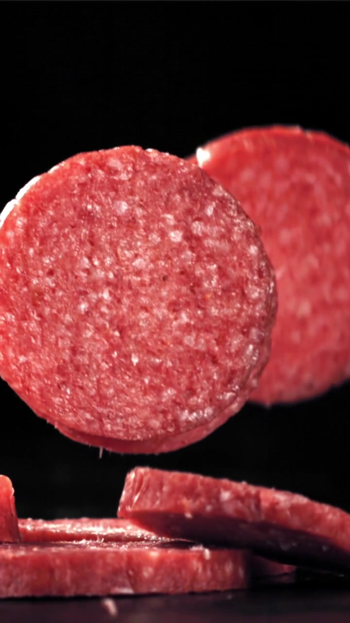 Fette di salame che cadono al rallentatore su sfondo nero