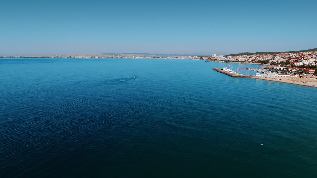 Coastal view of a vibrant seaside town. A bright sunny day showcases the calm sea and a lively beach in a coastal town bustling with activities