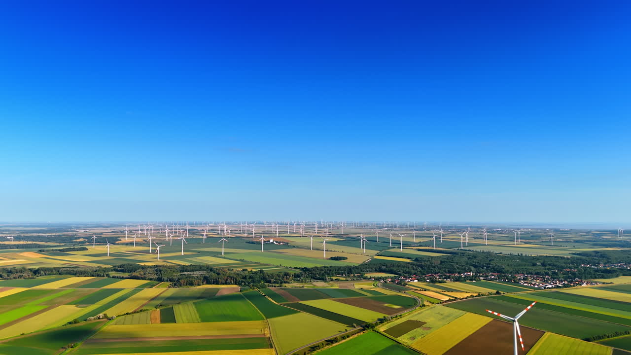 Vast beautiful fields with wind farms. Wind turbines rotate producing green energy. Aerial view.