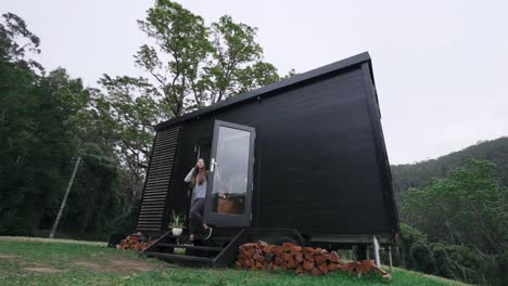 Female-hiker-leaving-secluded-wood-cabin-to-go-hiking