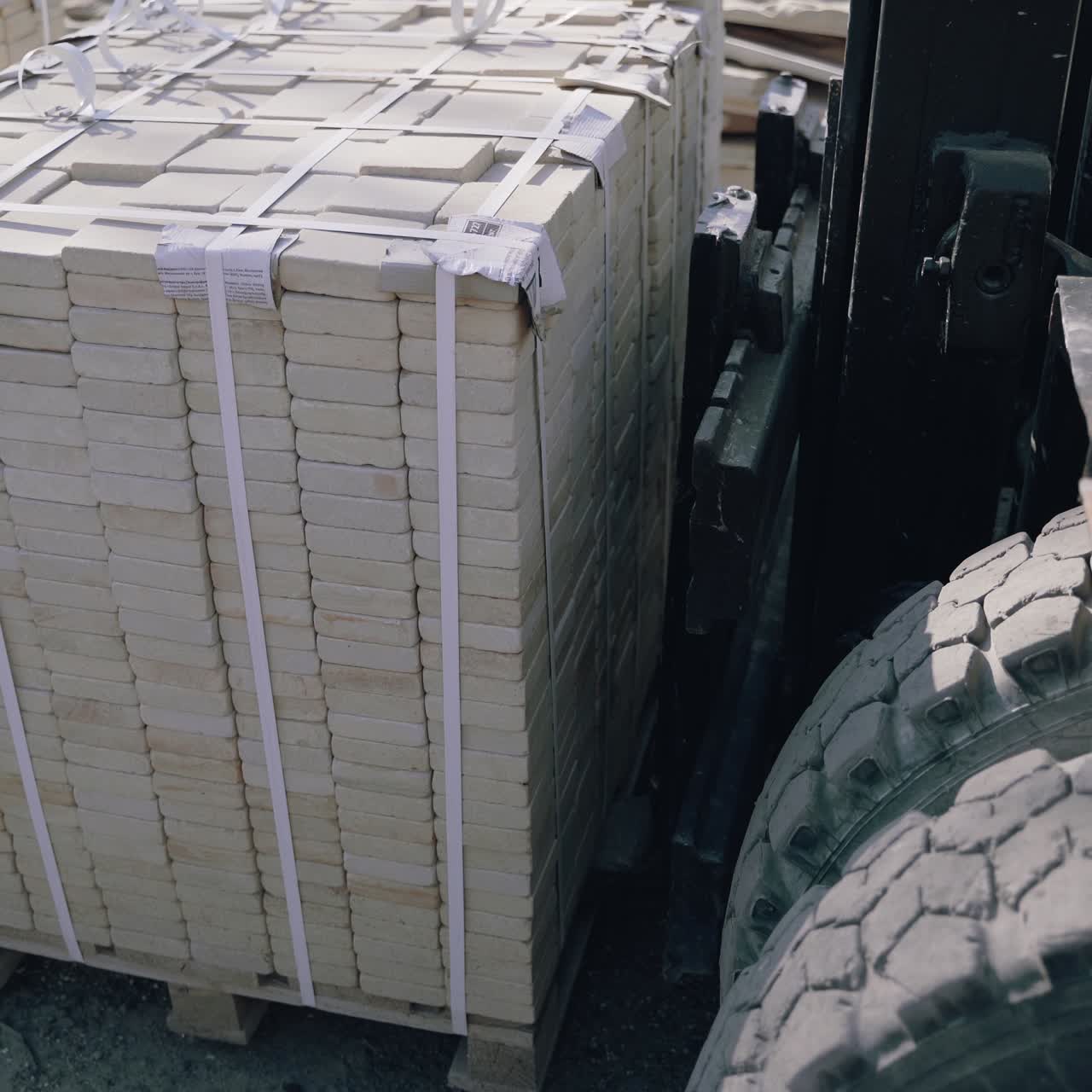 forklift is raising one pallet with a brick and takes it away in the yard of the factory.