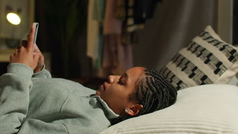 teenage girl lying in bed using smartphone