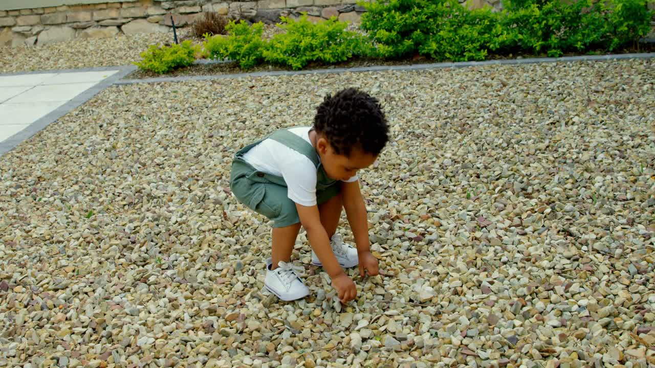 Vista frontale di un simpatico bambino nero che gioca nel giardino di casa sua 4k