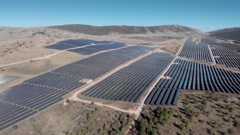 Absteigende-Drohne-über-Großen-Photovoltaik-Solarpark-Bauernhof-Reihenpaneelen-Sonniger-Tag