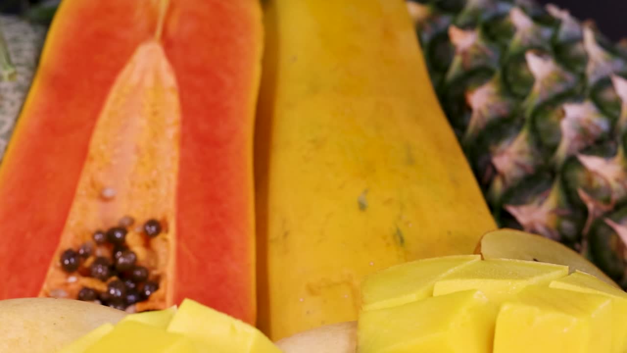 A vibrant display of tropical fruits including papaya, pineapple, kiwi, and pomegranate.