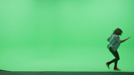 green screen chroma key studio: beautiful teenage girl wearing stylish casual clothes dances across room
