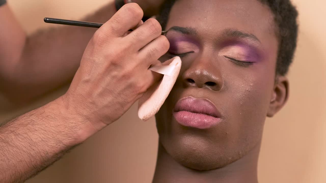 Crop visagiste filling in eyebrows of black transgender
