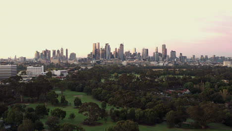 Friedlich-Rosa-Silhouettierte-Stadtbildluft-Von-Melbourne-Mit-Herrlichen-Farben,-Die-Den-Golfplatz-Darunter-Enthüllen