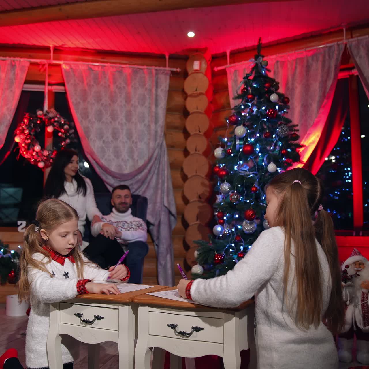 Cozy atmosphere at Christmas in the house. Happy parents talk together while little girls painting in the Christmas decorated room