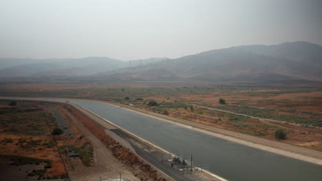 Vista-Aérea-Del-Acueducto-Y-Sendero-De-California-Cerca-De-Palmdale-En-Un-Día-Con-Neblina-Humeante-De-Incendios-Forestales