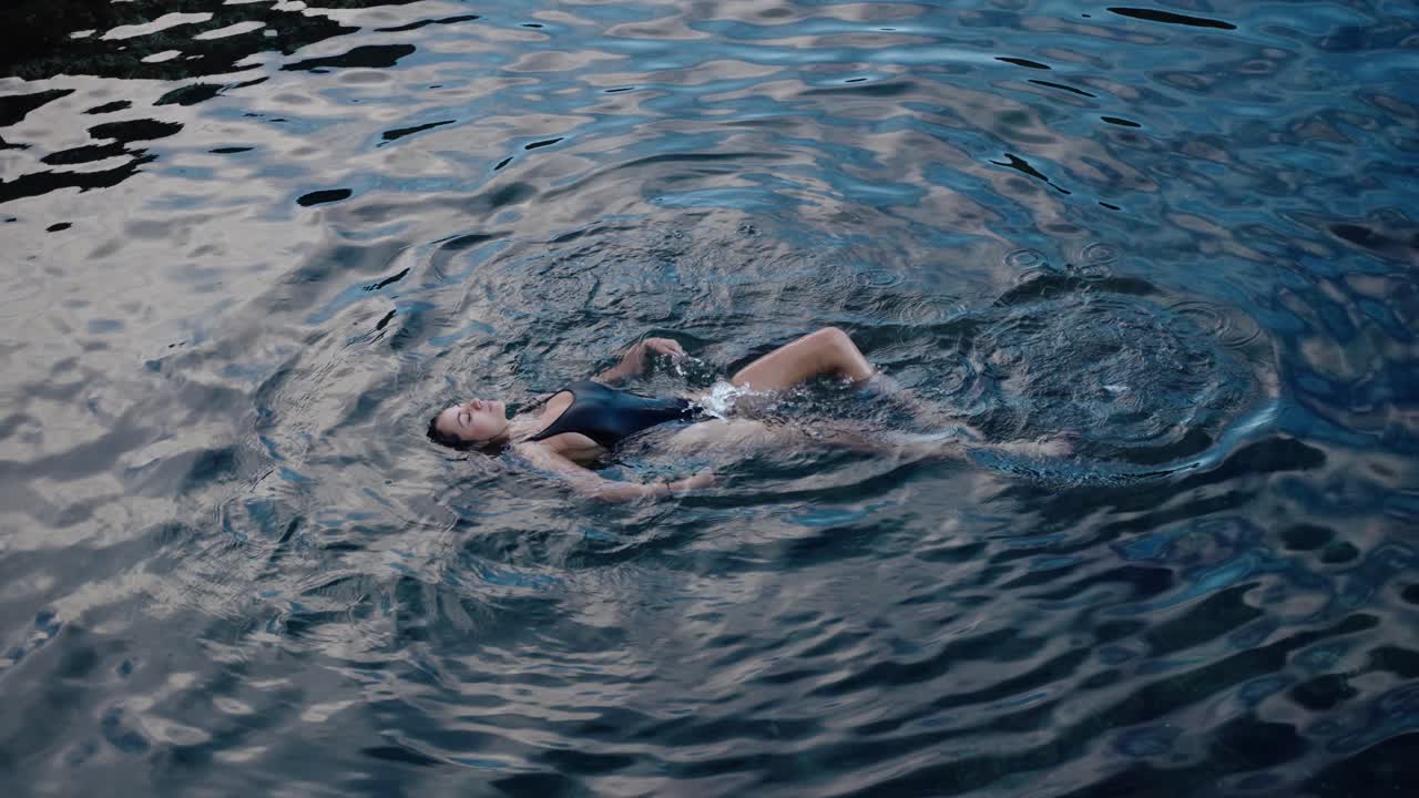 Woman peacefully floats on calm reflective waters in Seixal, Madeira, exuding grace and serenity in slow motion.