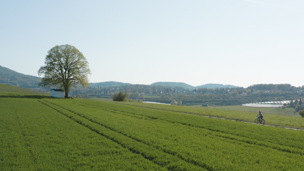 드론 - 자전거 타는 사람이 있는 풀밭에 있는 알 외로운 예배당의 공중 파노라마 샷과 7개의 산의 파노라마가 있는 도로 - siebengebirge 30p
