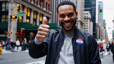 man with 'i voted' sticker in city giving thumbs up