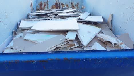 construction waste in a blue dumpster