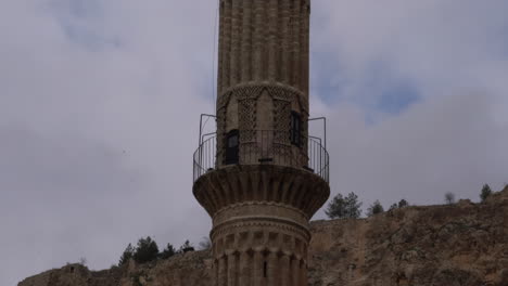 As-the-camera-tilts-down,-we-see-the-extraordinary-stonework-of-the-minaret-of-the-Şehidiye-Madrasa-in-Mardin