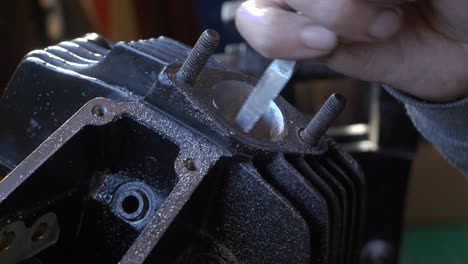 hands man files inside of a engine block cylinder