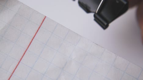 man puts black clamp on checkered paper sheets macro