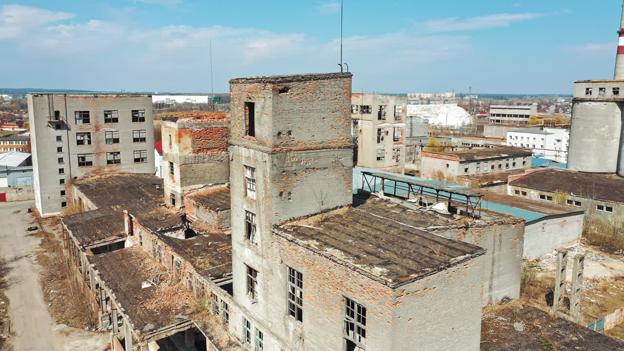 Damaged buildings with broken windows and pitted roof outside. Abandoned place with empty houses after military actions. Aerial view.