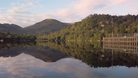 reflejo de espejo en un tranquilo lago de ullswater de colinas, bosques y cielo