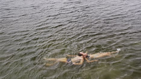 caucasian couple having a good time on a trip to the mountains, wearing bathing suits and floating o