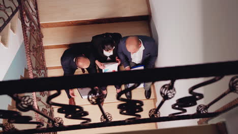 top view of project team looking on documents sitting on stairs