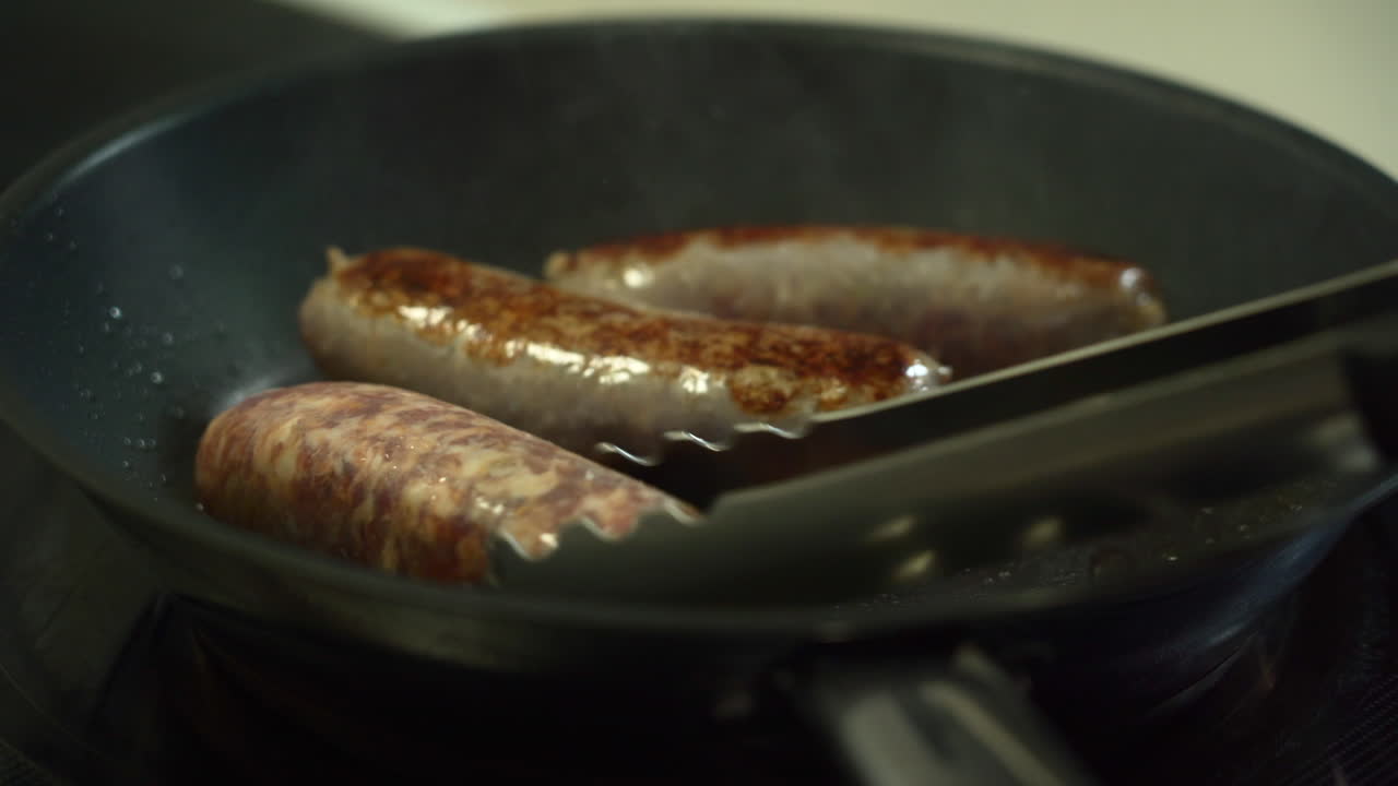The Chef is turning delicious sausages while searing them in a non stick pan