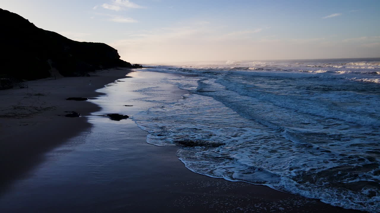 vuelo de drones que revela el amanecer mientras las suaves olas corren hacia la playa, el desierto, la ruta del jardín