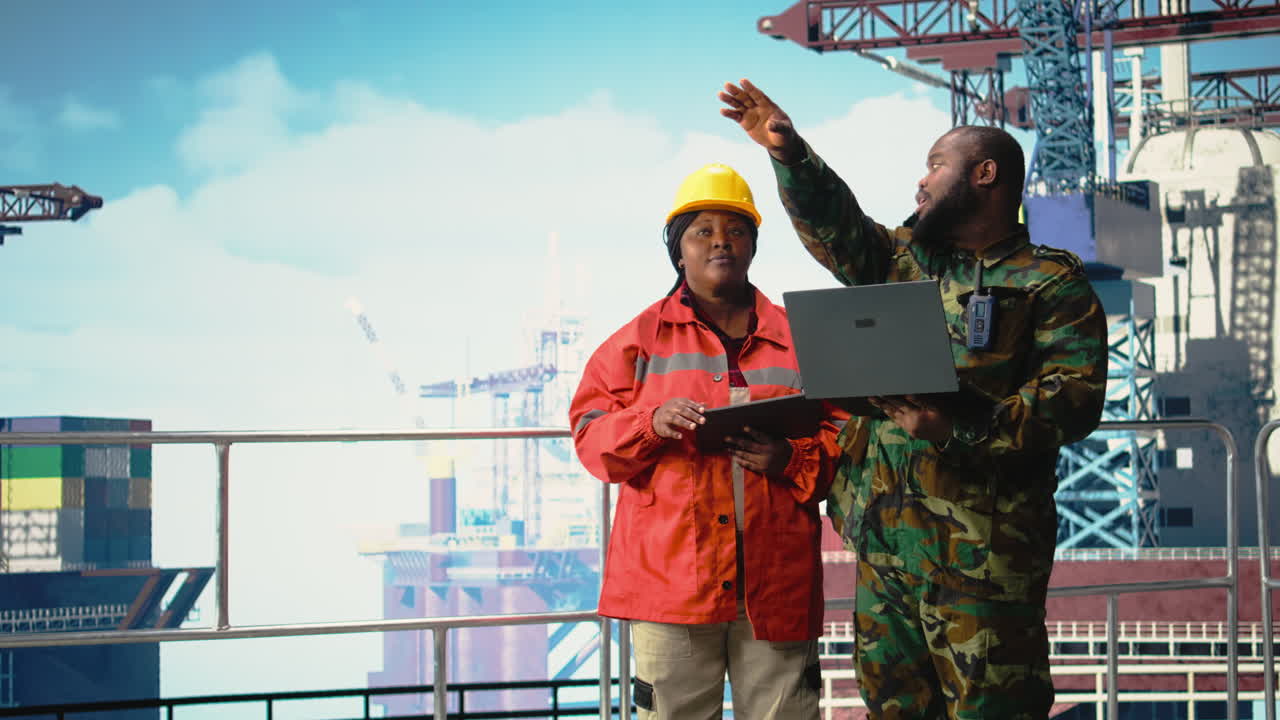 Vertical video Military personnel on offshore rig analyzing tactical data on laptop