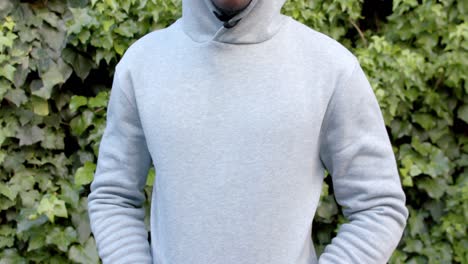 Midsection-of-african-american-man-wearing-grey-hooded-sweatshirt-top-in-garden,-slow-motion