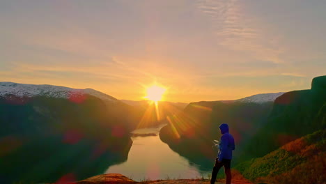 back view of man looking at breathtaking sunset over norwegian fjord