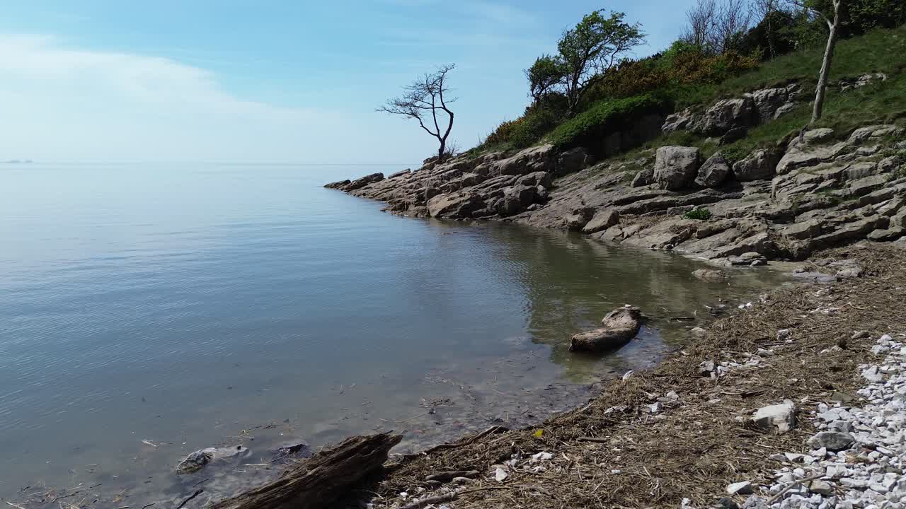 Private paradise rocky slope shoreline aerial view across calming dreamlike seascape and blue sky