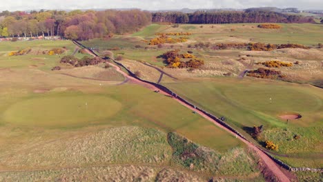 Campo-De-Golf-Escocés-Desde-El-Aire-Con-Un-Camino-Que-Atraviesa-Un-Día-Soleado