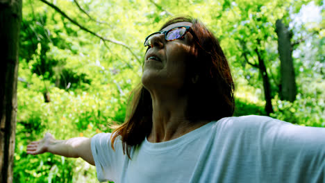 mujer madura de pie con los brazos extendidos en el jardín 4k