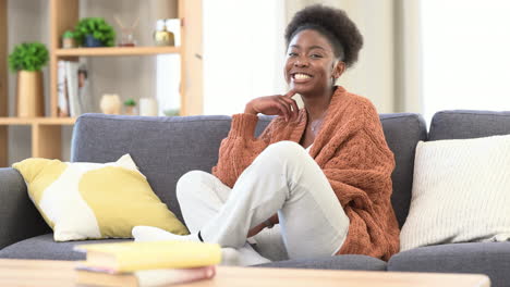 Happy-woman-looking-at-camera-smiling-on-sofa