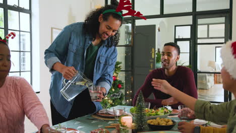 diverse friends celebrating christmas at home, sharing drinks and laughter by tree