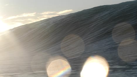 the golden glow of the rising sun as a short, heavy wave crashes