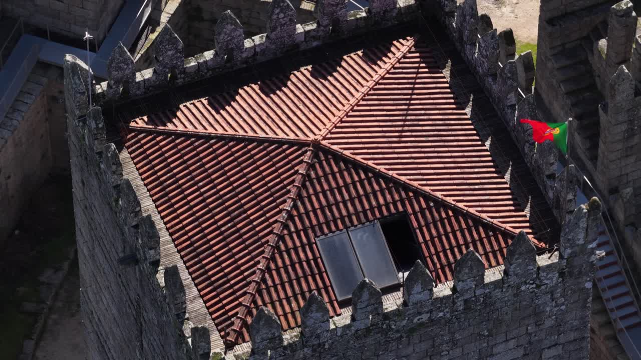 Ripresa con drone in orbita e zoom della torre del castello di Guimarães e della bandiera del Portogallo. Capitale verde europea. Patrimonio portoghese.