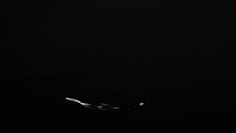sliced radishes drop onto a reflective black surface, creating splashes and dynamic movement in bright lighting