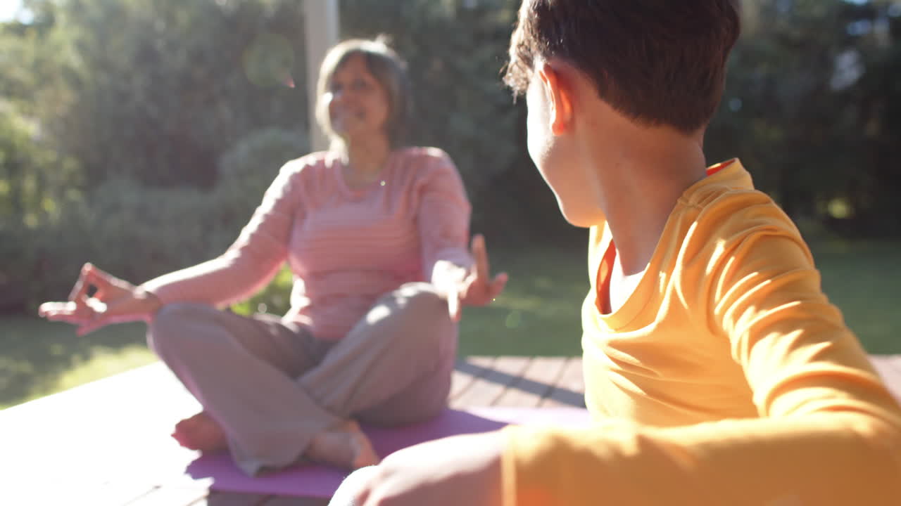 행복한 종족 할머니와 손자가 요가를 하고, 테라스에서 명상하고, 느린 동작을 하고