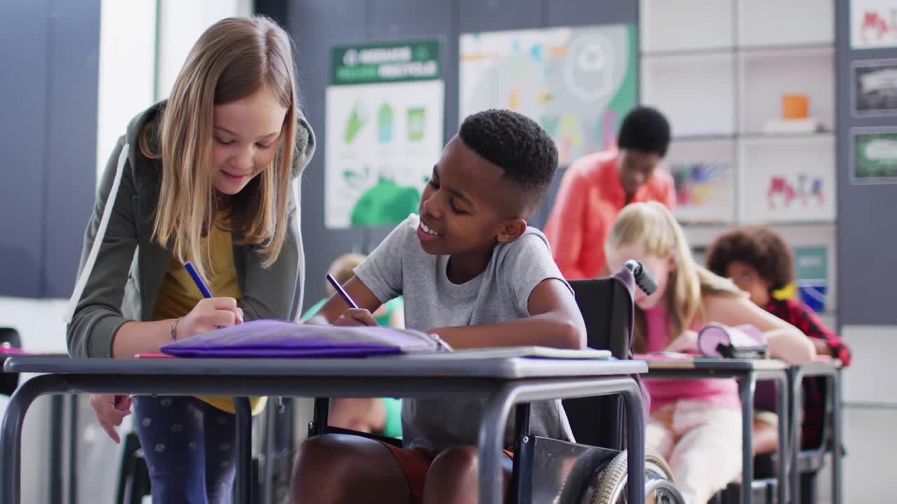 escolares diversos felices en los escritorios escribiendo en el aula de la escuela